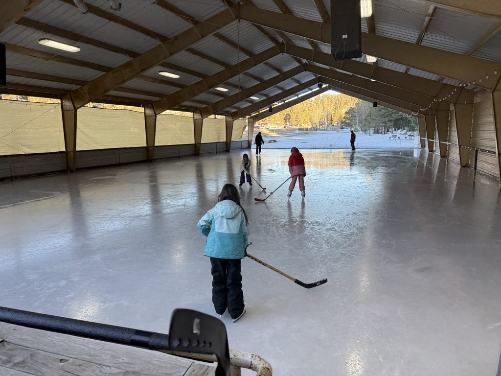 Kids playing hockey on the ice under the covered pavilion at the James Sewell Ice Rink at Zenith Park
