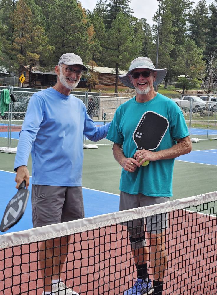 Two men shaking hands at the net after a match on the Cloudcroft courts