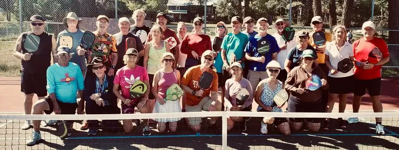 Large group photo of the Pickleball Addicts of Cloudcroft club members posing with paddles