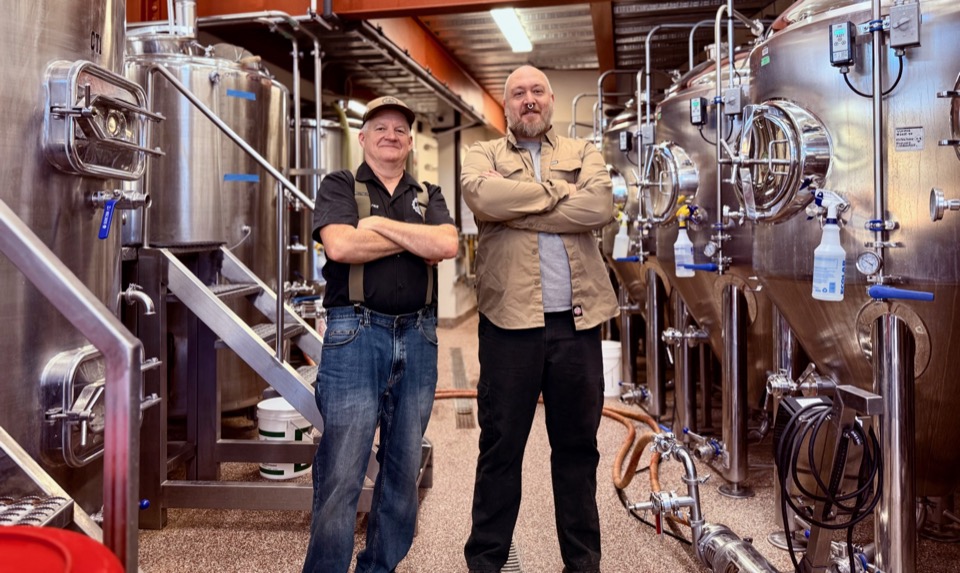 Two brewers between rows of fermentation tanks at Cloudcroft Brewing