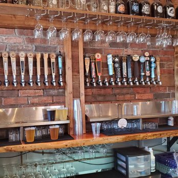 Tap wall behind the bar with brewery glassware stacked overhead