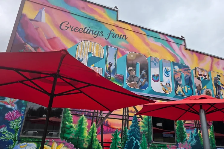 South-patio &lsquo;Greetings from Cloudcroft&rsquo; mural close-up by local artist Samantha Odom, with red sun umbrellas in the foreground