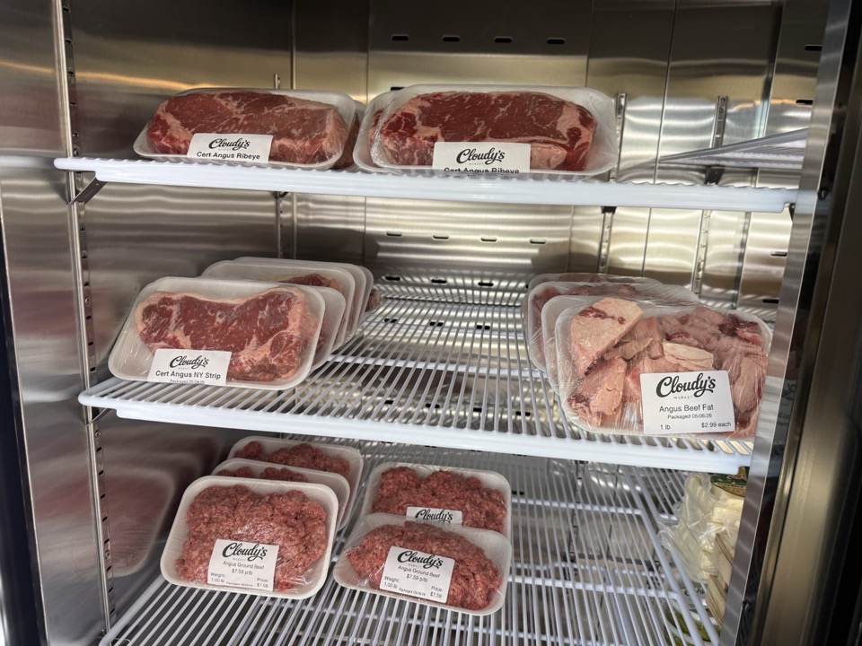 Cloudy's-labeled fresh-meat case with Certified Angus ribeye steaks, NY strip, ground beef, and beef fat — packaged under the store's own brand