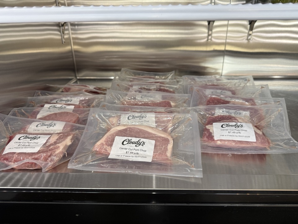 Vacuum-sealed center-cut pork chops in Cloudy's Market branded packaging at $7.49 per pound, arranged on the meat case
