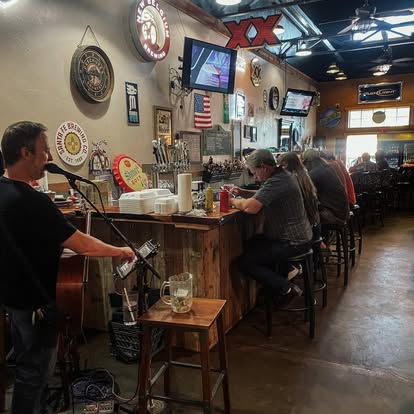 Bar scene with live musician and patrons at Dave's Café