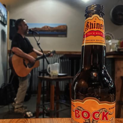 Shiner Bock beer on the bar with live guitarist performing at Dave's Café