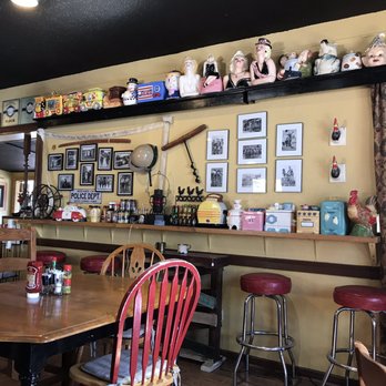 Interior detail at Dusty Boots Café — bar with red stools, vintage figurines on a shelf, framed black-and-white photographs on the wall