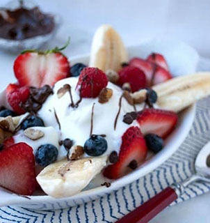Yogurt parfait with strawberries, banana, blueberries, raspberries, granola, and chocolate drizzle