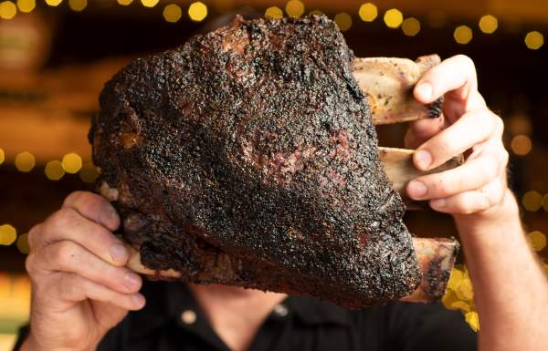 Massive smoked beef rib (Dino rib) held up at Mad Jack's BBQ