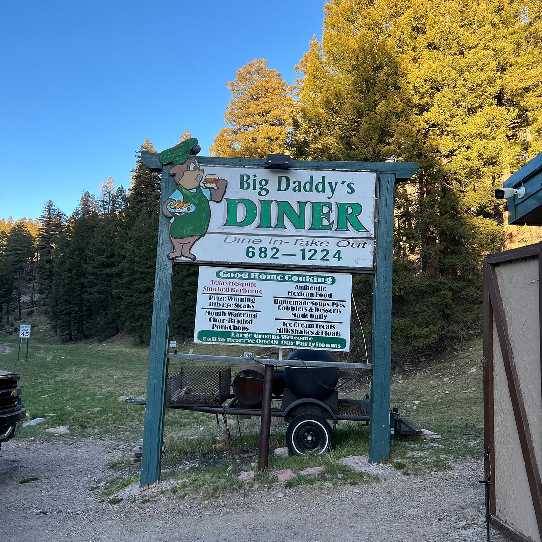 Big Daddy's Diner roadside sign with smoker and mountain pines