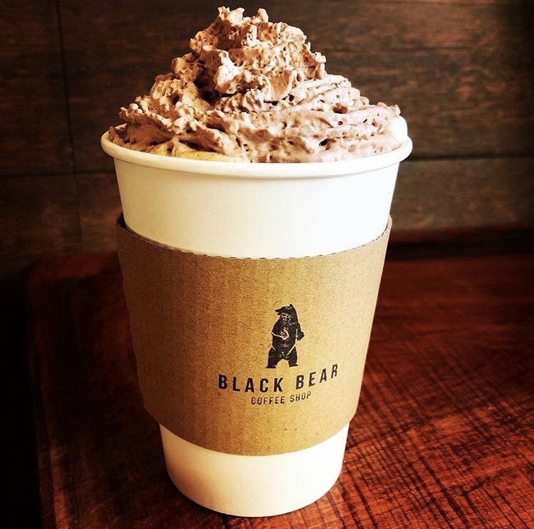 Black Bear Coffee branded cup with Cloudcroft downtown in the background