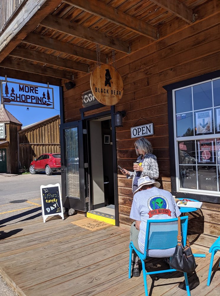 Sidewalk view with outdoor seating and signage at Black Bear Coffee