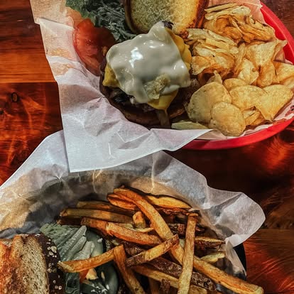 Burger with melted cheese and chips alongside fresh-cut fries at Dave's Café