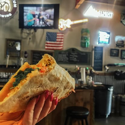 A wrap held up inside Dave's Café with American flag and neon signs in the background