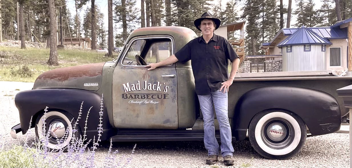 Pitmaster James Jackson standing next to the Mad Jack's BBQ vintage truck in Cloudcroft