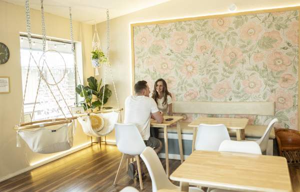 Cozy interior of High Rollin' Coffee with floral accent wall and hammock chair