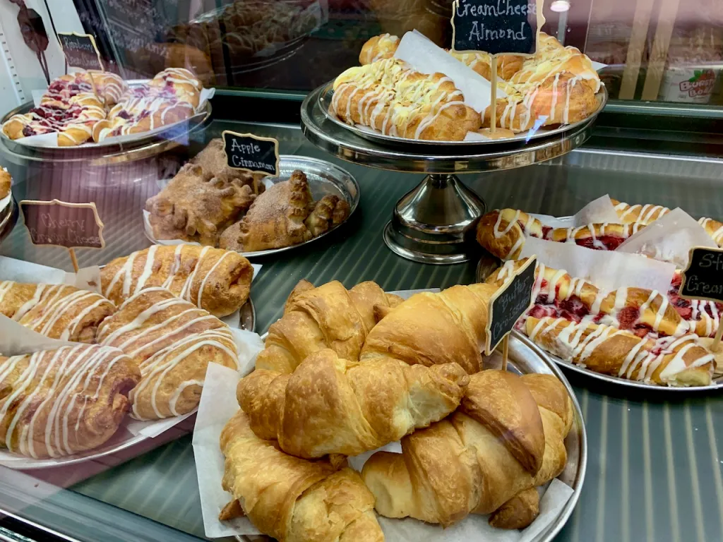 Bakery case filled with croissants, pastries, and iced Danish at KennaBelles