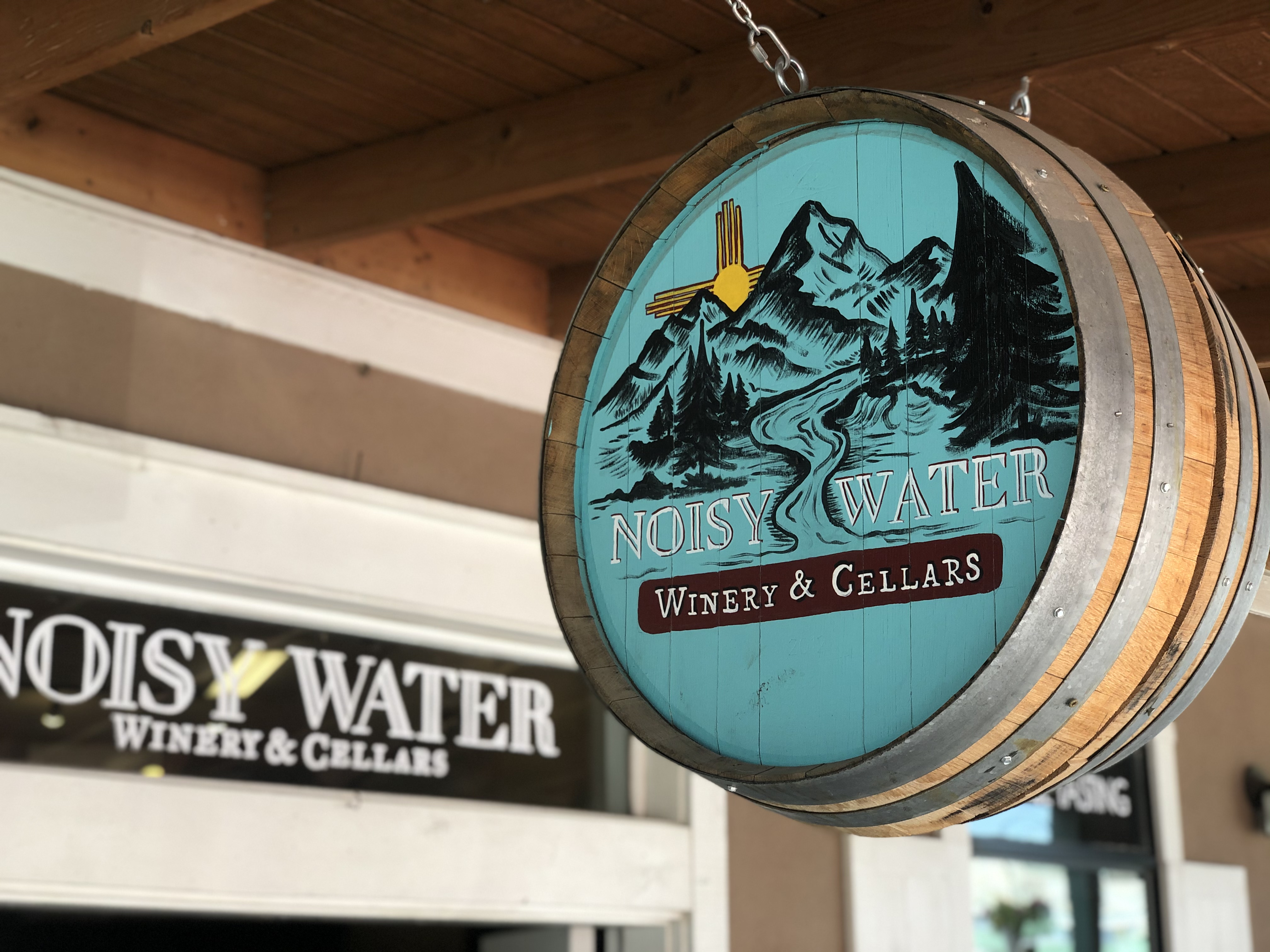 Noisy Water Winery barrel sign with mountain scene and Zia symbol on Burro Avenue