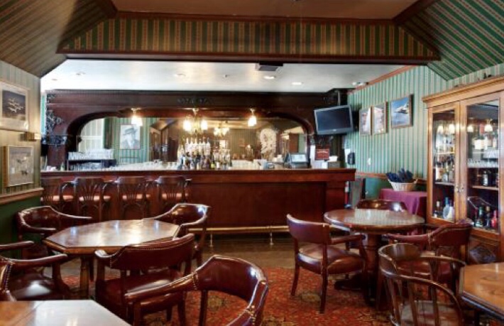 Leather chairs and round tables in the lounge seating area at St. Andrew's Bar