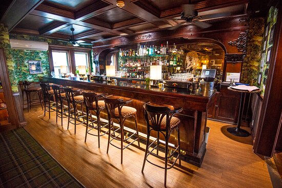 Bar counter with high stools, backlit bottles, and coffered ceiling at St. Andrew's
