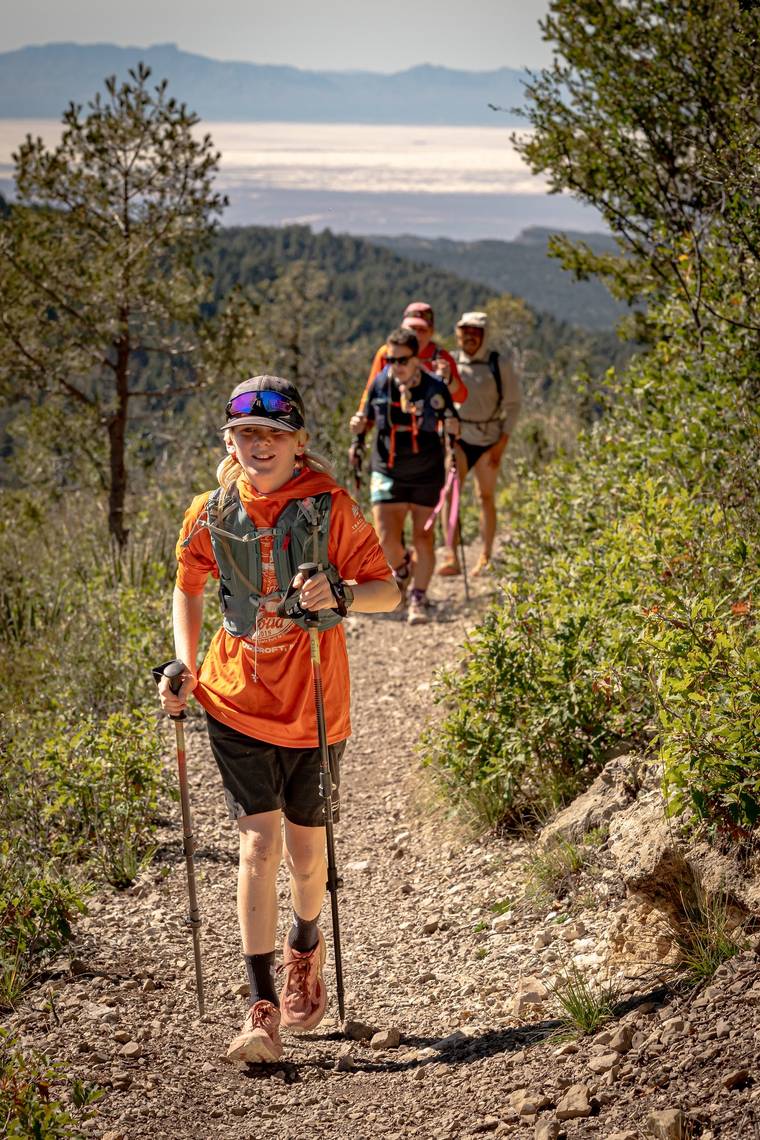 Runners with trekking poles climbing a rocky trail high above the Tularosa Basin during the Cactus to Cloud Sky Race