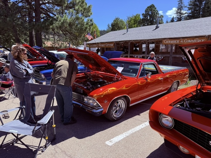 Classic cars with hoods raised at the Heritage Day Car Show outside the Cloudcroft Chamber of Commerce