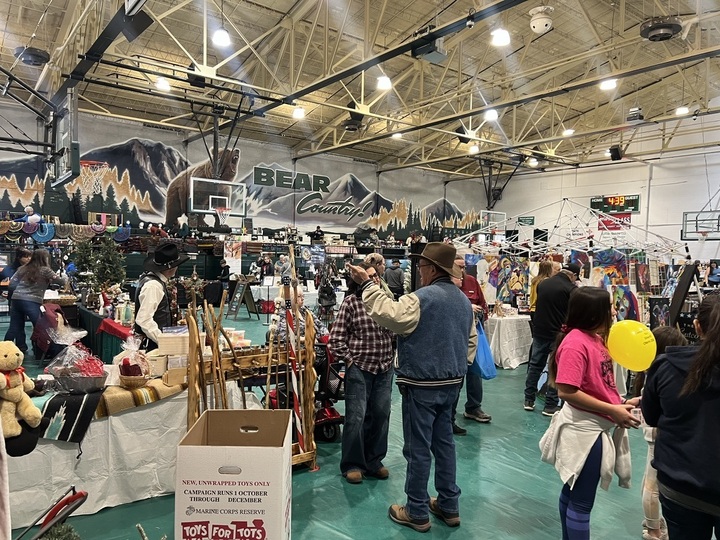 Cloudcroft Christmas Market vendors set up under the Bear Country mural at the school gym, with shoppers browsing handmade goods