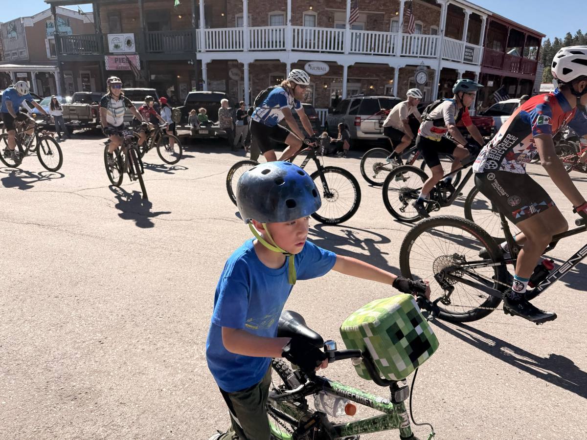 Young rider with a Minecraft Creeper handlebar bag while adult racers roll by behind