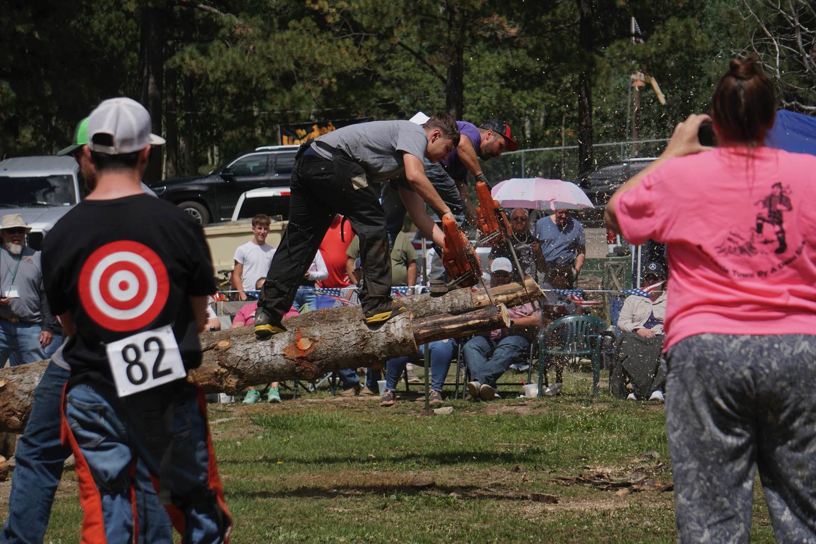 Competitor cutting through a log with a chainsaw in front of the crowd at Cloudcroft Lumberjack Day