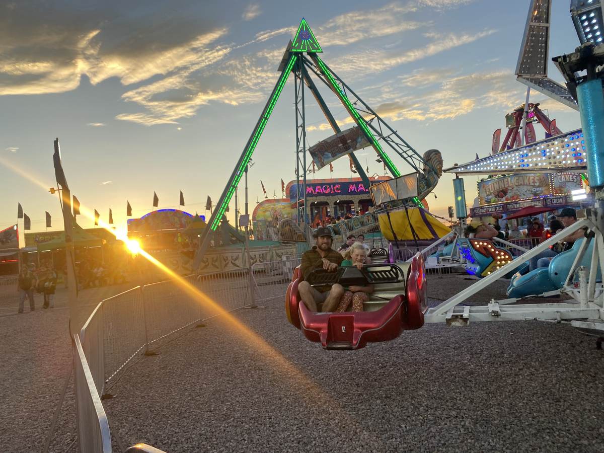 Carnival rides lit up on the midway at sunset at the Otero County Fair