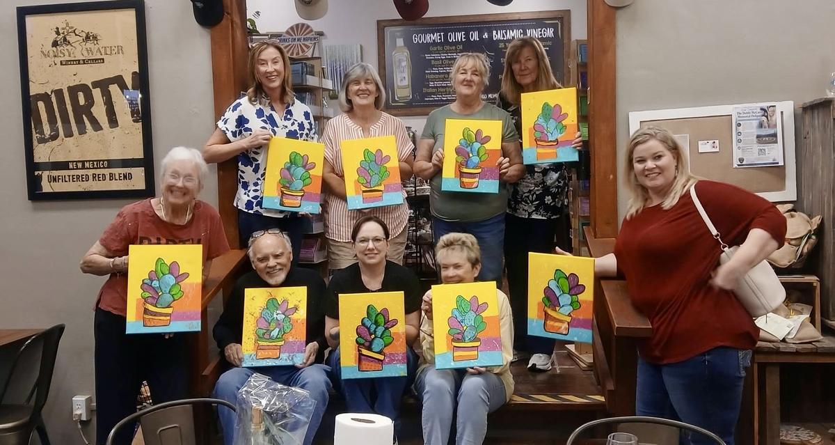 A paint class holding up their finished cactus canvases at the Noisy Water Winery tasting room in Cloudcroft