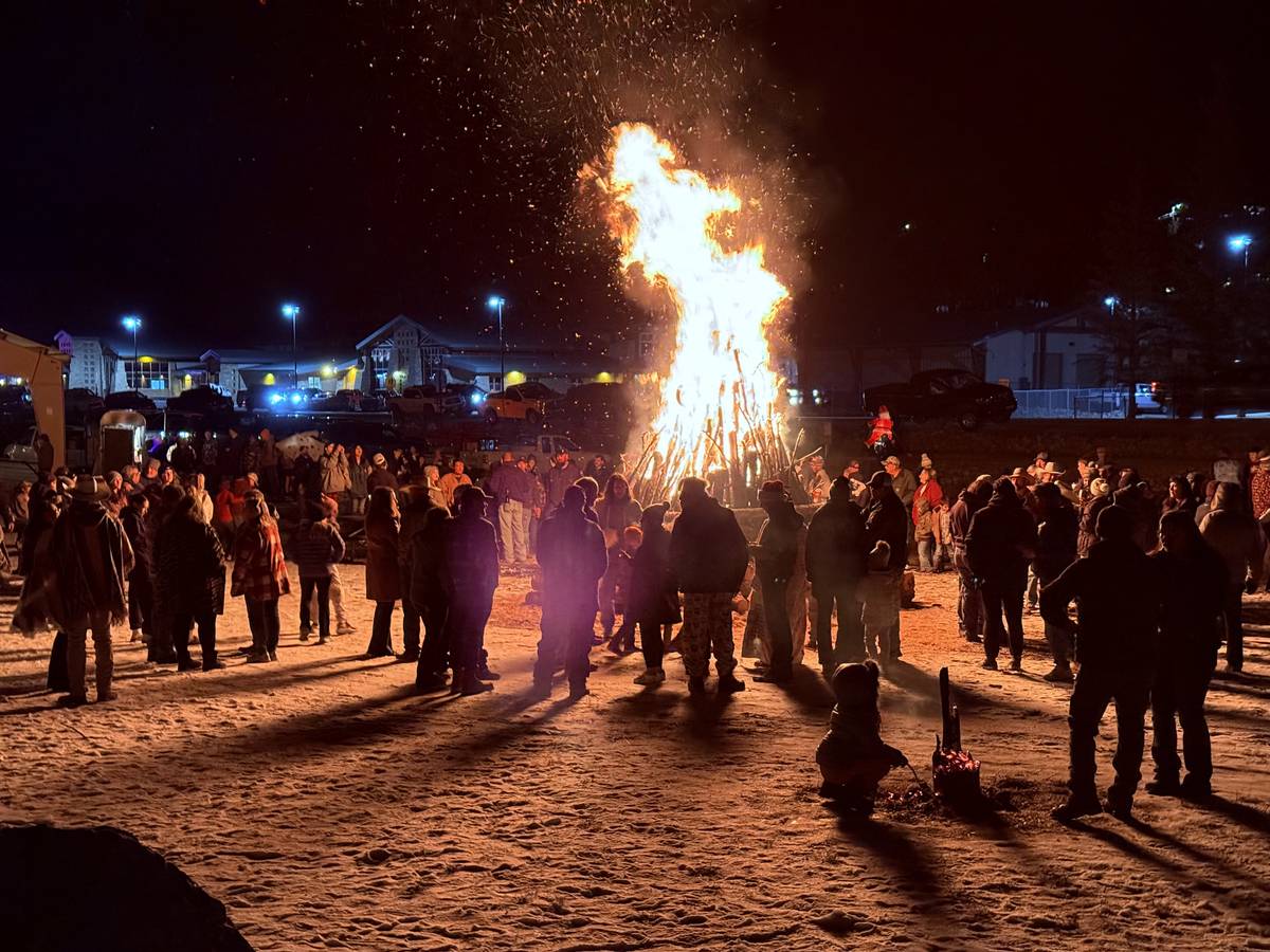 Crowd circled around the tall UllrFest bonfire at night at Zenith Park in Cloudcroft