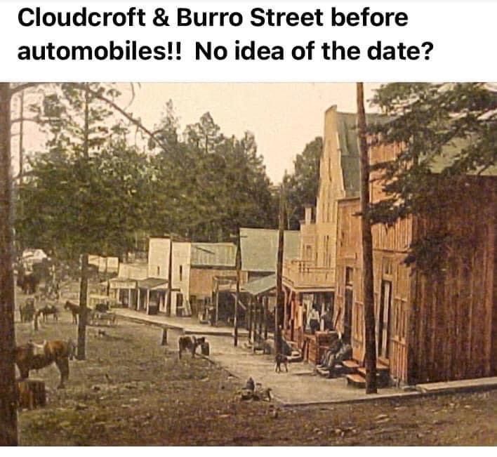 Early hand-tinted photograph of Burro Street in Cloudcroft before automobiles, with burros and wooden storefronts along a dirt street