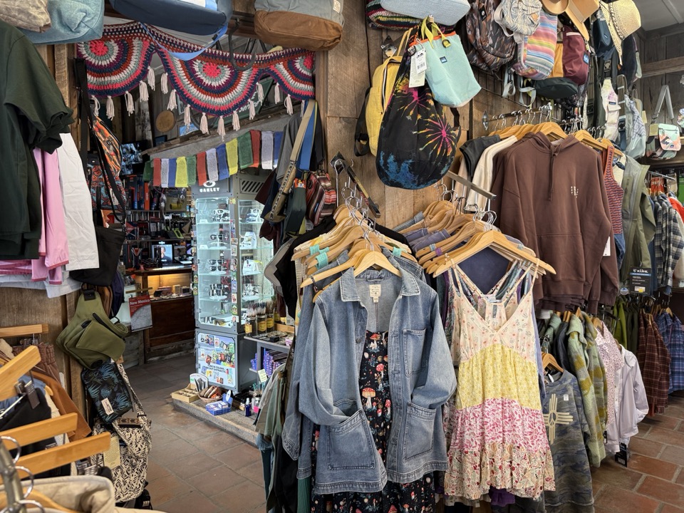 Boutique side at High Altitude with denim jackets, sundresses, hats, prayer flags strung above a jewelry case