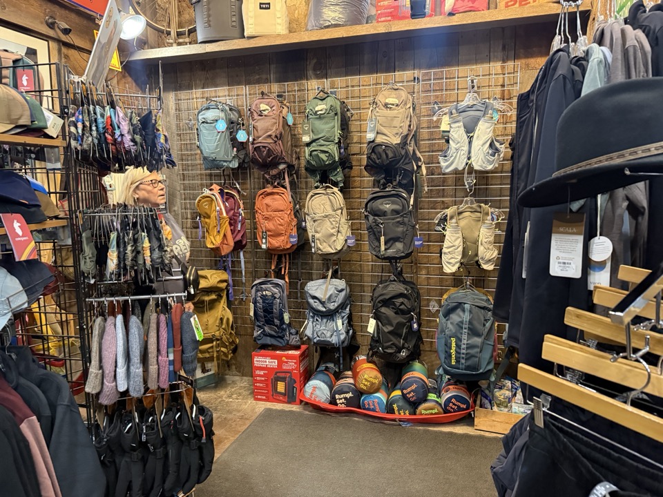 Backpack and daypack wall at High Altitude with hiking packs, hydration vests, and water bottles