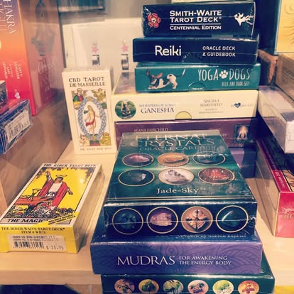 Stack of tarot and oracle decks at Instant Karma including Smith-Waite, Reiki, Yoga Dogs, Crystals, Mudras, and CBD Tarot