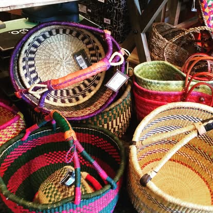 Stacked colorful woven baskets in pink, green, and purple at Instant Karma