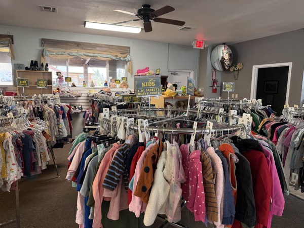 Children's clothing section at King's Treasure with circular rack of kids' jackets and heavy coats under a ceiling fan
