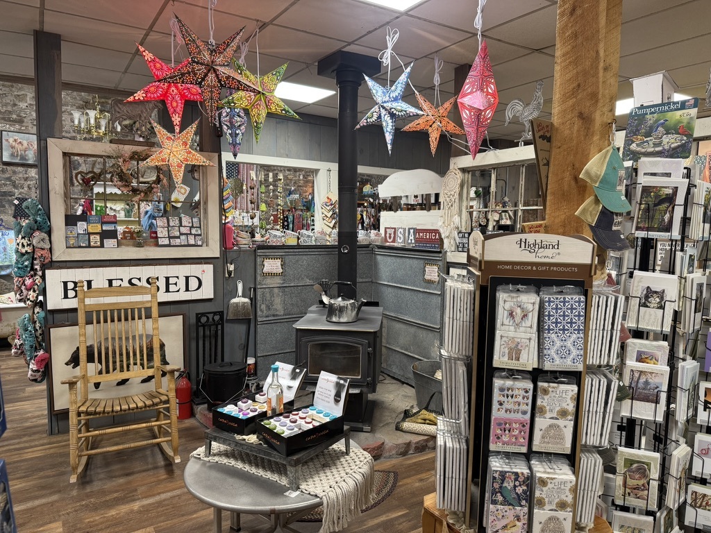 Wood stove surrounded by hanging paper stars, country décor, and Highland Home cards at Mountain Magic