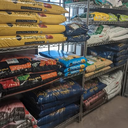 Garden aisle at New Village Hardware with bags of Sta-Green potting mix and other soil products on metal shelving