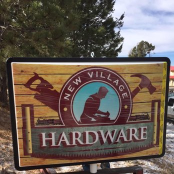Painted wooden New Village Hardware sign with a hammer and saw flanking a silhouetted figure