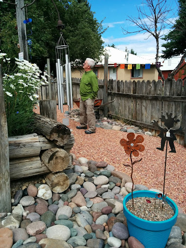 Outdoor sculpture garden with river-rock landscaping, wind chimes, and rusted-metal flower sculptures