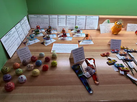 Table of handmade ceramic &lsquo;adoptable&rsquo; figurines with hand-written certificates of adoption