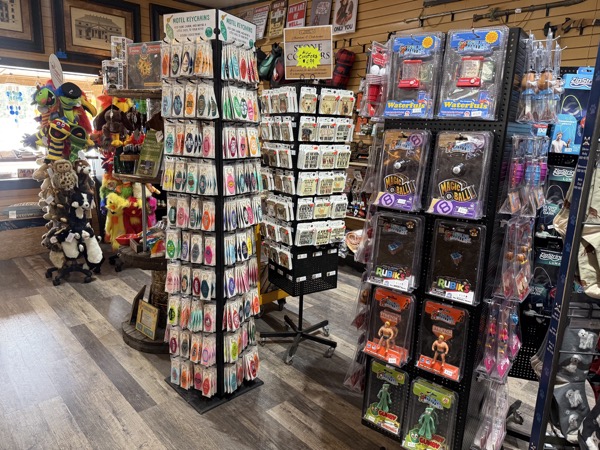 Spinner racks of novelty keychains, Magic 8 Balls, Rubik's cubes, water-gun toys, and small action figurines at Poke The Bear