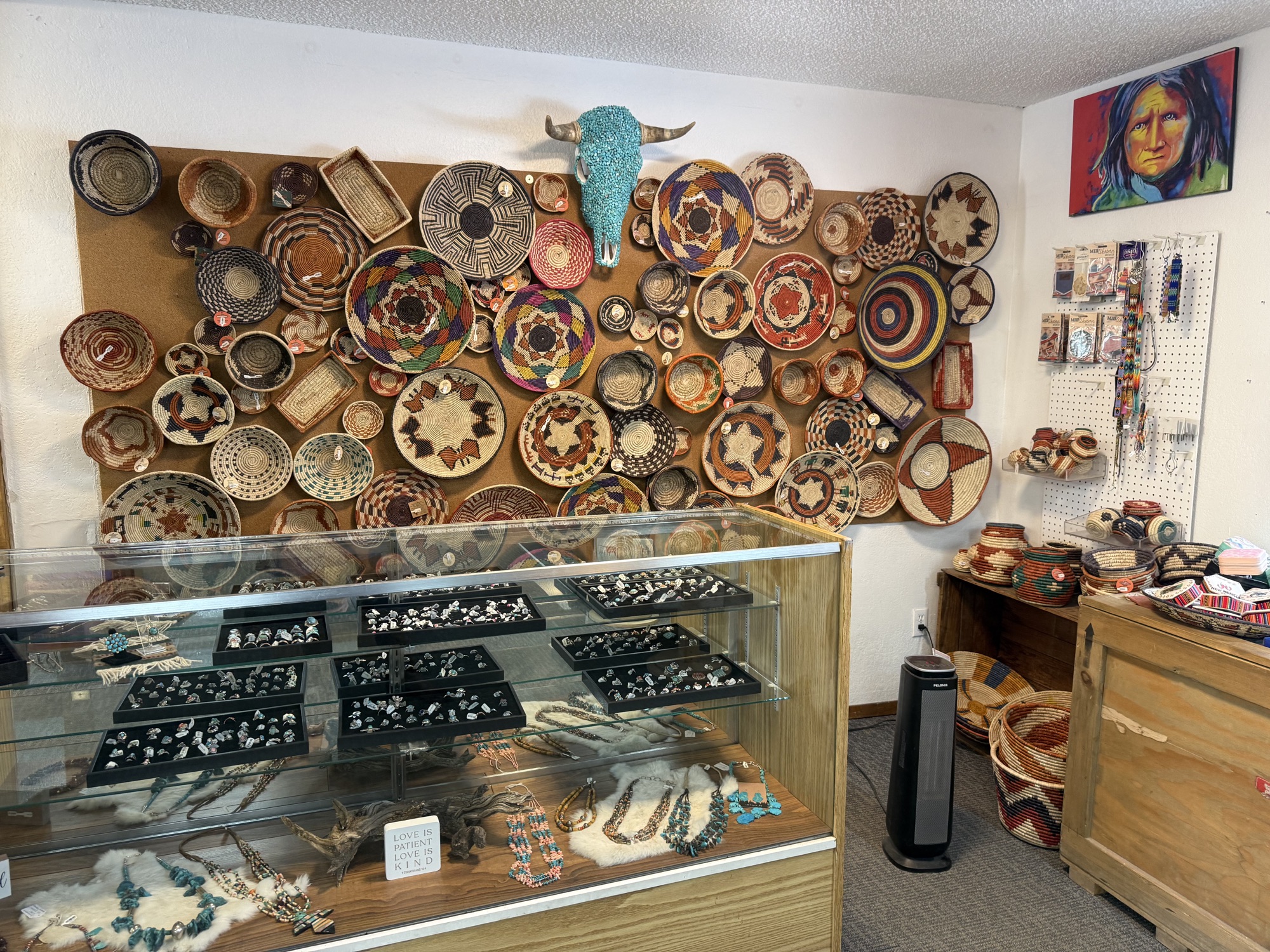 Wall of woven Native American baskets above lit jewelry display cases at The Turquoise Shop