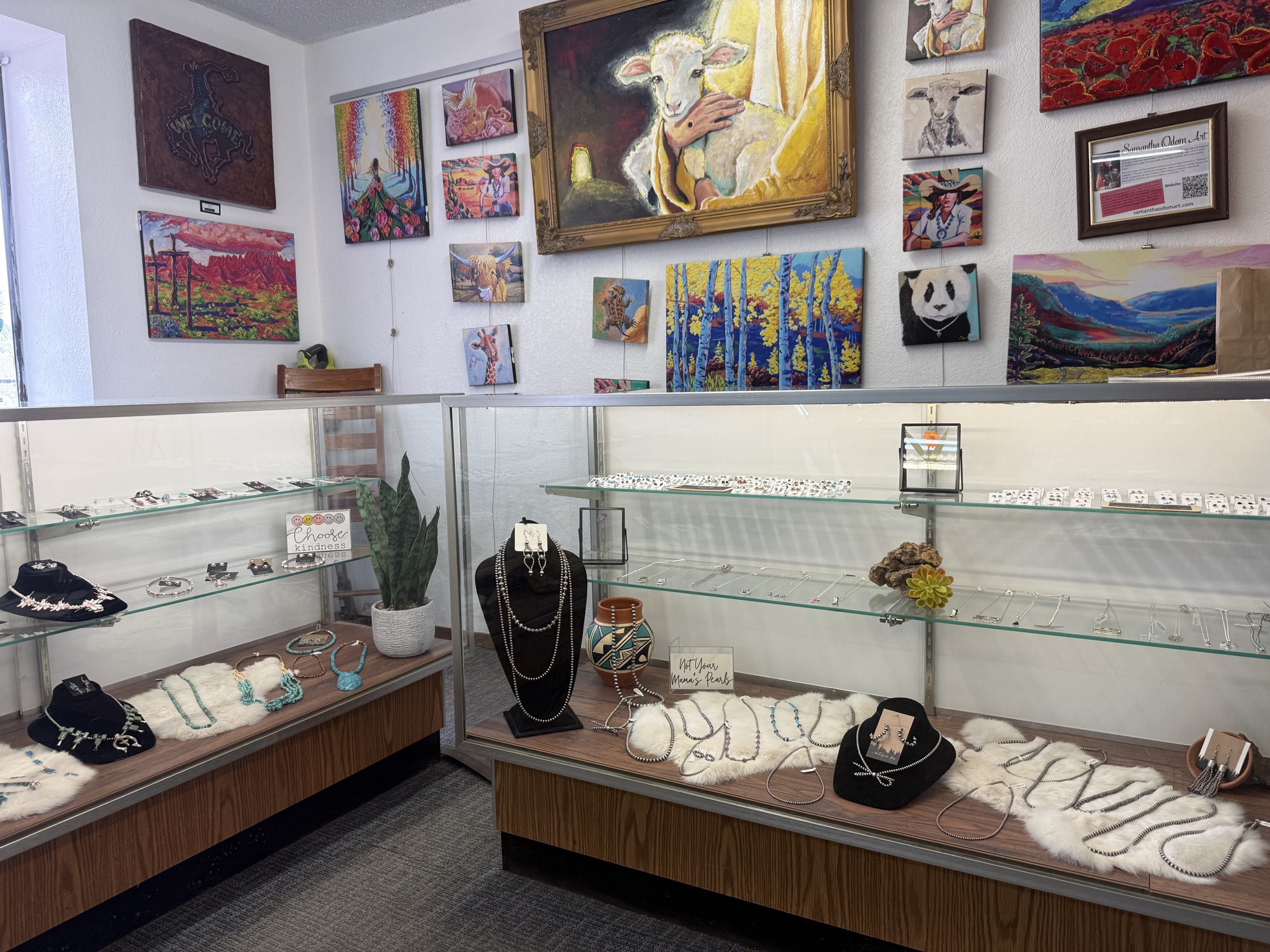 Jewelry cases set beneath a wall of paintings and Southwest art