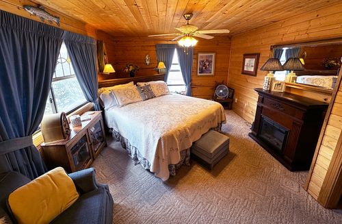 Marine Room at Burro Street Boardinghouse with king bed, light bedding, blue curtains, fireplace, and ceiling fan