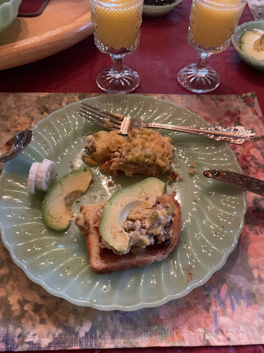 Home-cooked breakfast plate at Burro Street Boardinghouse with avocado, eggs, toast, and mimosa-style juice glasses