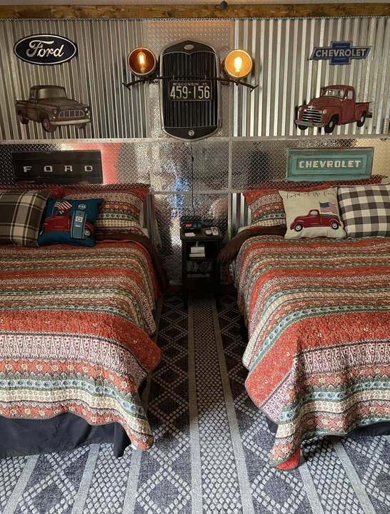 Ford and Chevy themed twin-bed room with vintage truck art and corrugated metal walls