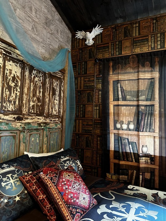 Harry Potter themed room with bookshelf wallpaper, Hedwig owl, and tapestry-draped headboard